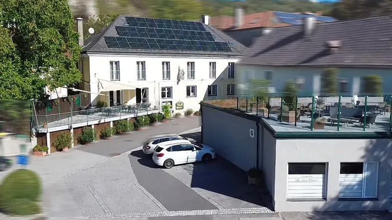 Luftaufnahme des Anwesens mit Hauptgebäude, Parkplätzen und umliegender Landschaft.