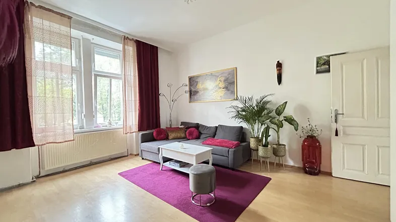 Helles Wohnzimmer mit Holzboden, bequemer Couch und dekorativen Pflanzen.