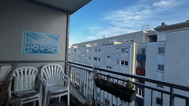 Balkon mit Blick auf die umliegenden Gebäude und den blauen Himmel am Morgen.
