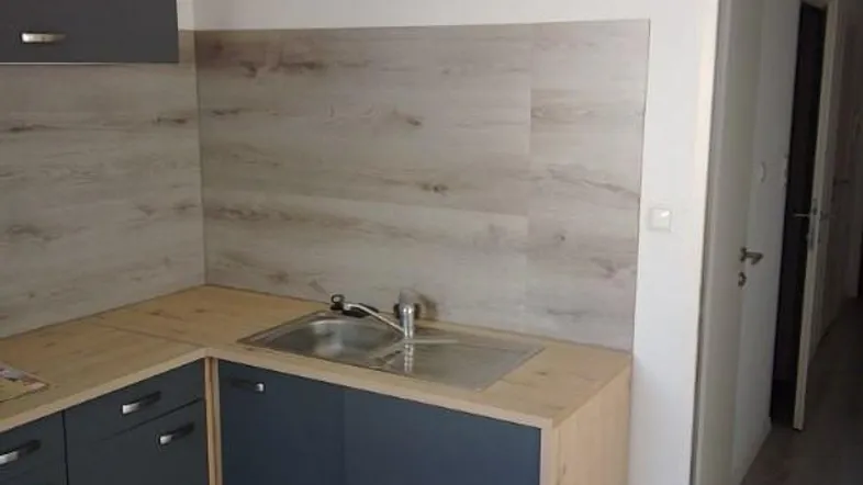 Moderne Küche mit grauen Unterschränken, Holzoptik-Arbeitsplatten und Spülbecken, bereit für weitere Geräte.
