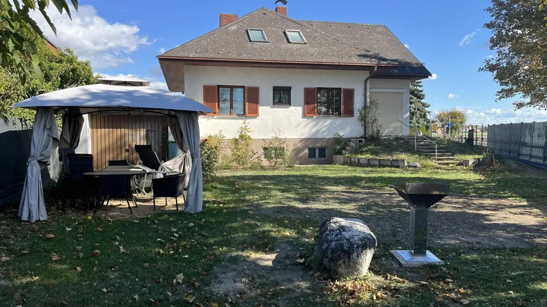Großer Garten mit Rasenfläche, Grillplatz und überdachtem Sitzbereich für entspannte Stunden im Freien.