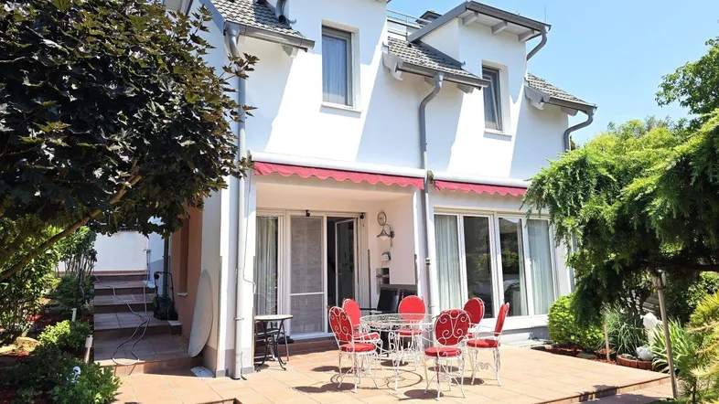 Geräumige Terrasse mit Gartenmöbeln und Markise, umgeben von gepflegtem Grün und Bäumen.