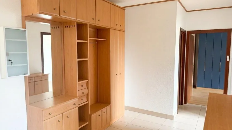 Heller Flur mit praktischem Einbauschrank, Spiegel und Fliesenboden, der zu weiteren Räumen führt.