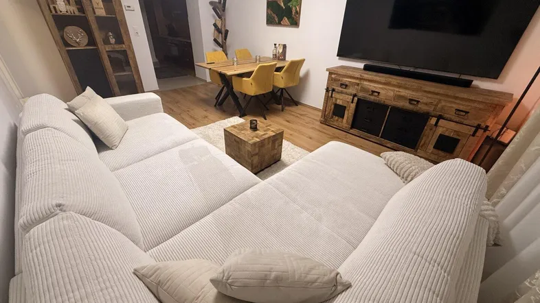 Helles Wohn- und Esszimmer mit großem Sofa, Esstisch und Holzboden.