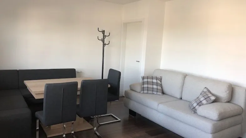Heller Wohn- und Essbereich mit dunklem Holzboden, bequemer Sitzecke und Sofa.