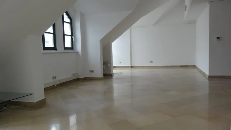 Geräumiger Wohnbereich mit schrägen Wänden, Dachfenstern und hellen Fliesenböden, der viel natürliches Licht erhält.