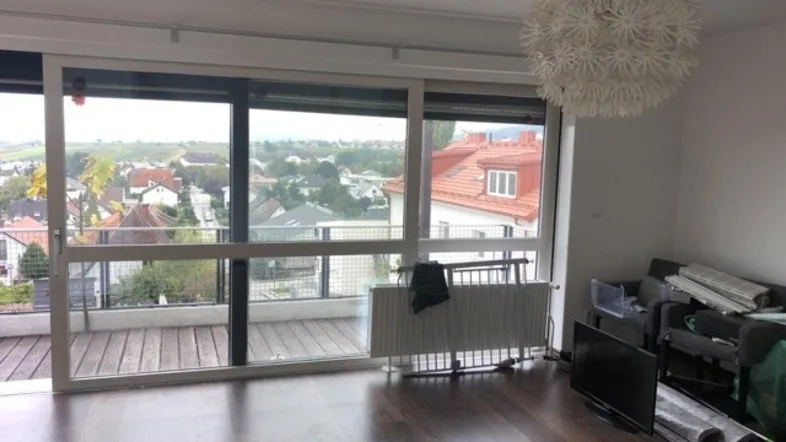 Helles Wohnzimmer mit dunklem Holzboden, großen Fenstern und Zugang zu einer Terrasse mit Weitblick.