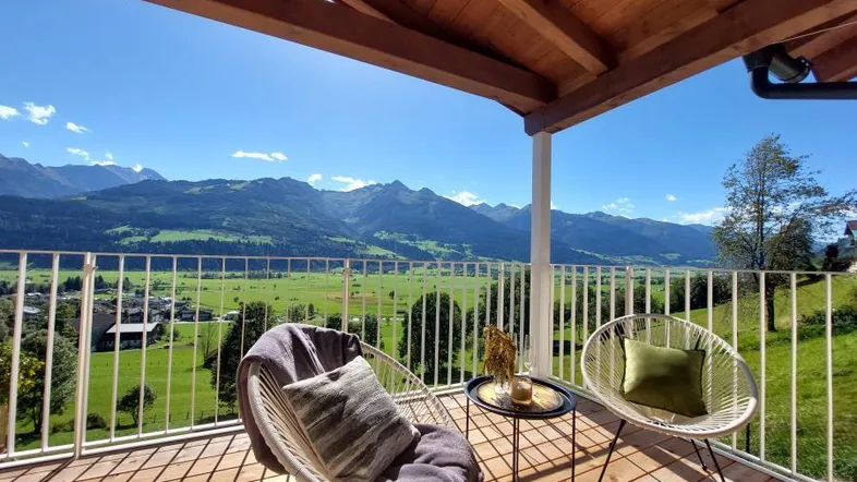 Geräumiger Balkon mit Holzboden, gemütlichen Sitzgelegenheiten und atemberaubendem Bergblick.