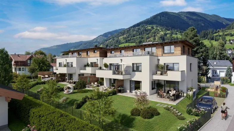 Moderne Wohnanlage mit mehreren Einheiten, umgeben von grünen Gärten und mit Bergblick.