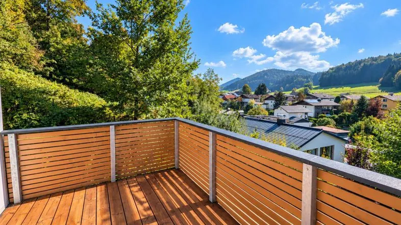 Geräumiger Balkon mit Holzboden und Lattenzaun, der einen weiten Blick auf die Landschaft bietet.