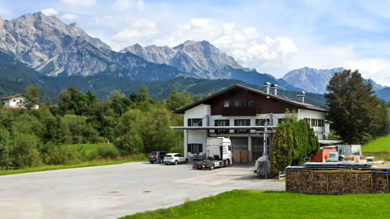 Gebäude mit ländlicher Umgebung und beeindruckendem Alpenpanorama im Hintergrund.