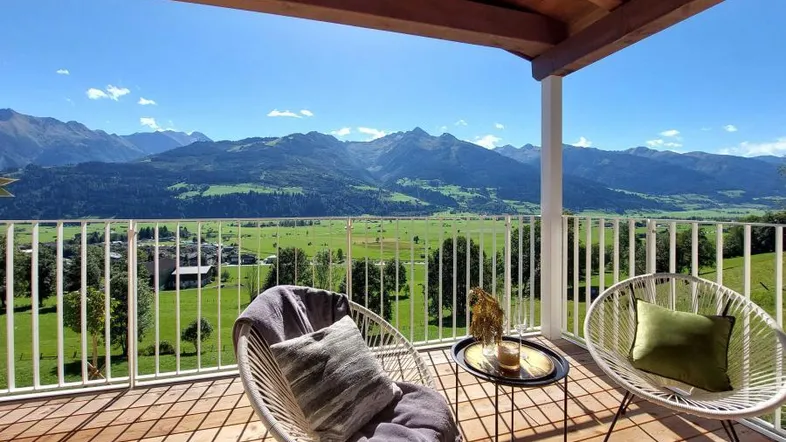 Geräumiger Balkon mit Holzboden, bequemen Sitzgelegenheiten und atemberaubendem Bergblick.