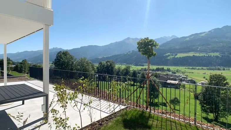 Geräumige Terrasse mit Blick auf die umliegende grüne Landschaft und die majestätischen Berge.
