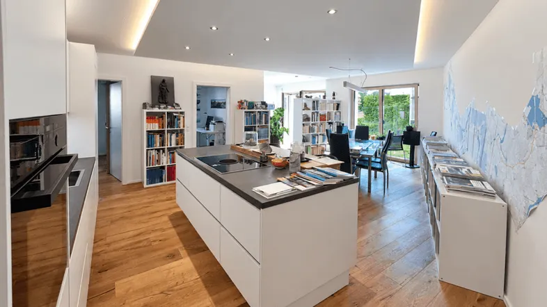 Moderner offener Wohn-Essbereich mit integrierter Küche, Holzboden und Blick in den Garten.
