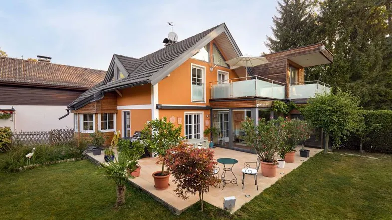Charmantes Haus mit großer Terrasse und gepflegtem Garten, umgeben von viel Grün.