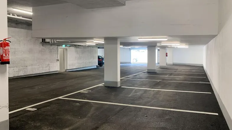 Geräumige Tiefgarage mit markierten Stellplätzen, guter Beleuchtung und Brandschutzvorrichtungen.