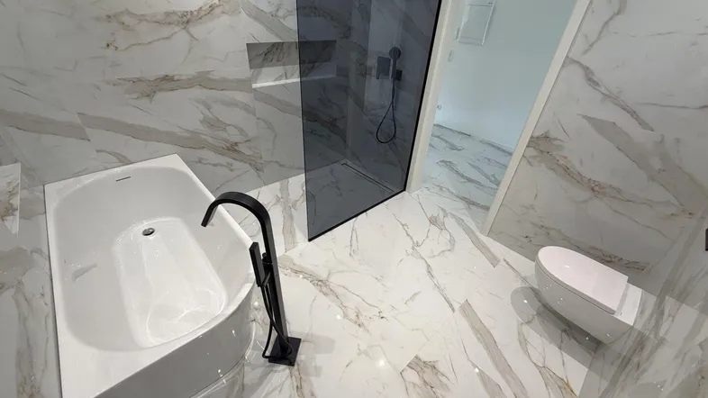 Modernes Badezimmer mit Marmorfliesen, freistehender Badewanne und begehbarer Dusche.