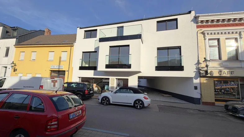 Moderne Wohnfassade mit Balkonen und großen Fenstern an einer belebten Straße.