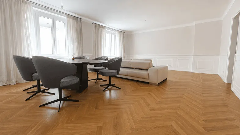 Heller Wohn- und Essbereich mit Fischgrätparkett, modernem Esstisch und beigem Sofa.