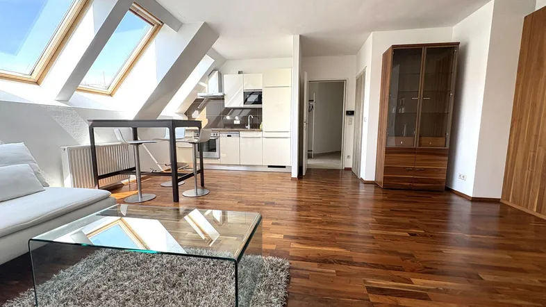 Heller offener Wohnbereich mit Holzboden, Dachfenstern und integrierter Küche in modernem Design.