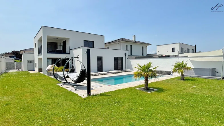 Moderne Villa mit großem Garten, privatem Pool und gemütlichen Hängesesseln im Freien.