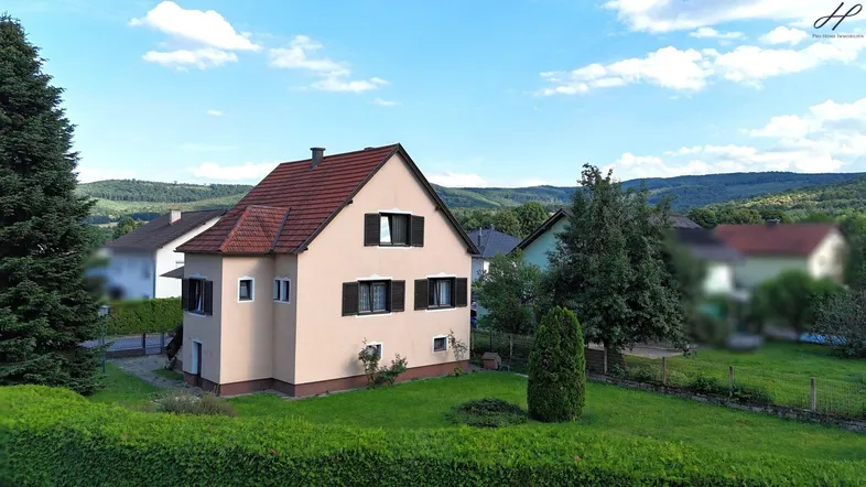 Freistehendes Einfamilienhaus mit großem Garten und Blick auf die umliegende Hügellandschaft.