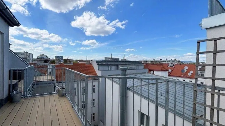 Geräumige Dachterrasse mit Holzboden und weitem Blick über die Stadt und die umliegenden Dächer.