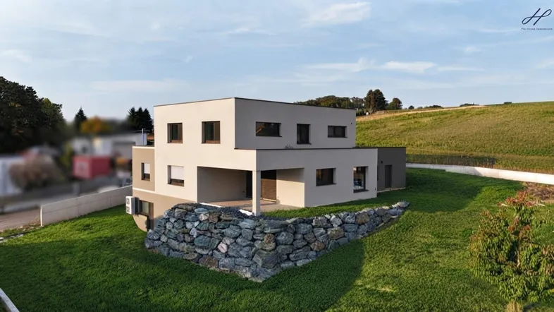 Modernes Einfamilienhaus mit flachem Dach, großen Fenstern und gepflegtem Gartenbereich.