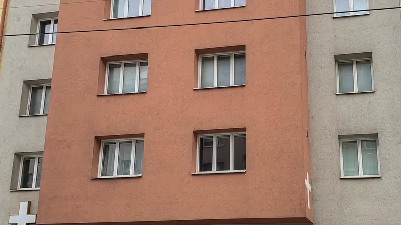 Mehrstöckiges Gebäude mit einer markanten orangefarbenen Fassade und weißen Fenstern in städtischer Umgebung.