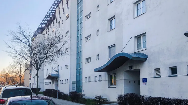 Moderne Wohnhausfassade in Weiß mit großen Fenstern und einem markanten vertikalen Glaselement.