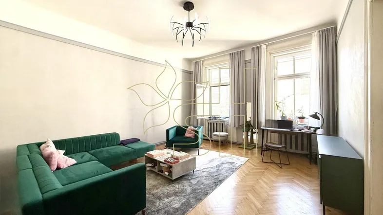 Helles Wohnzimmer mit Fischgrätparkett, grünen Samtmöbeln und zwei großen Fenstern.