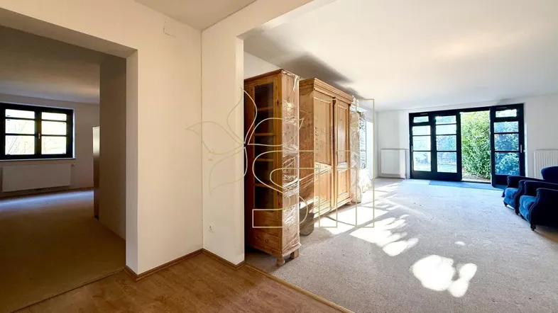 Heller Wohnbereich mit Teppichboden, großem Holzschrank und Zugang zum Garten.