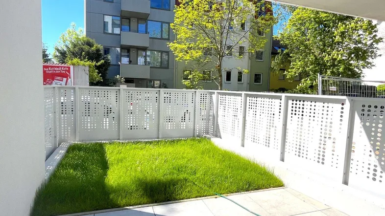 Kleiner privater Gartenbereich mit Rasenfläche und gefliestem Terrassenabschnitt in urbaner Umgebung.