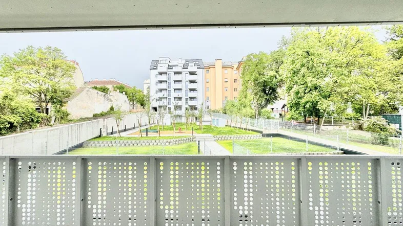 Blick vom Balkon auf eine gepflegte Grünfläche und moderne Wohngebäude in der Umgebung.