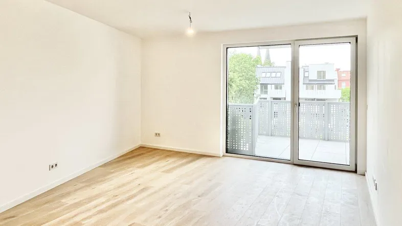 Helles, unmöbliertes Zimmer mit Holzboden und Zugang zu einem Balkon, ideal für individuelle Gestaltung.