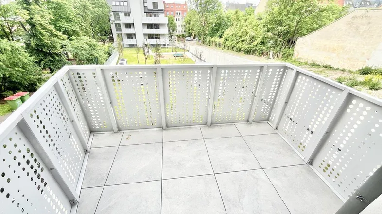 Geräumiger Balkon mit Fliesenboden und modernem Geländer, bietet einen weiten Ausblick ins Grüne.