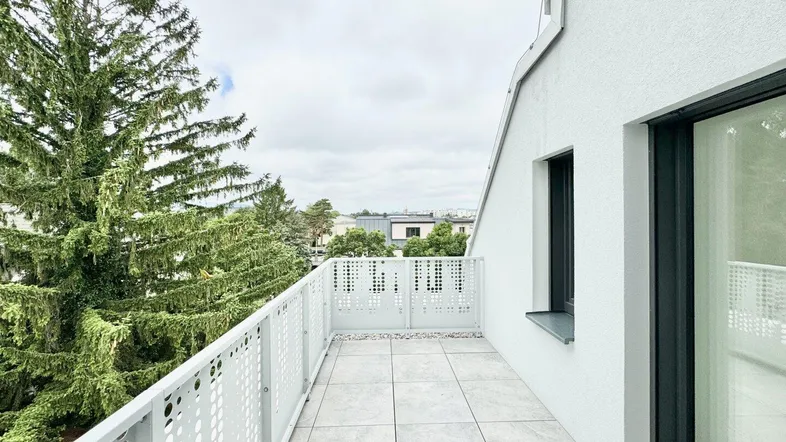 Geräumiger Balkon mit moderner Lochblechbrüstung und Blick ins Grüne.