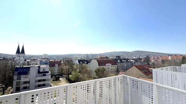 Balkon mit modernem Geländer und weitem Blick über die Stadt und die umliegende Landschaft.