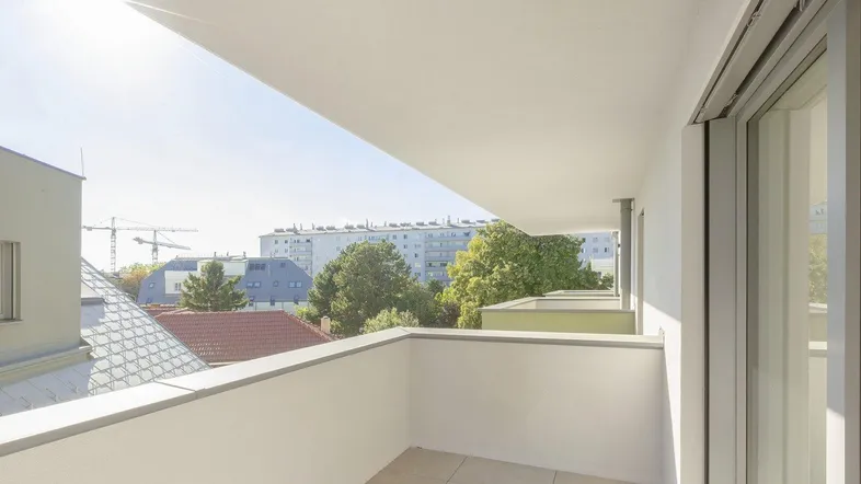 Heller Balkon mit Fliesenboden und weitem Blick über die Stadt und grüne Bäume.