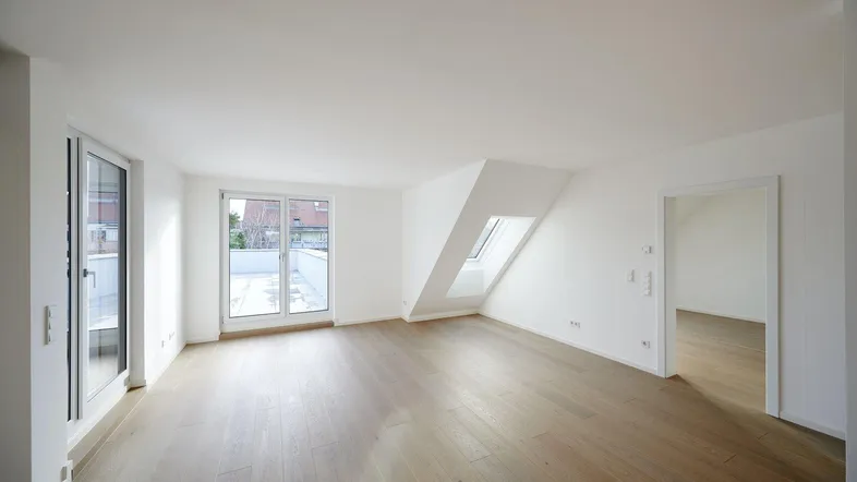 Helles, leeres Zimmer mit Holzboden, Dachschrägen und Zugang zu einer Terrasse.