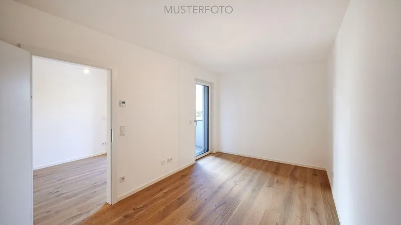 Heller Raum mit Holzboden und Zugang zu einem Balkon oder einer Terrasse.