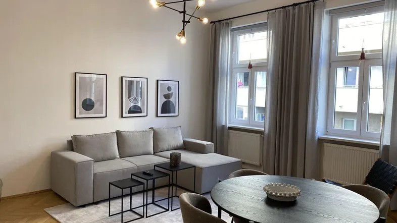 Heller Wohn- und Essbereich mit modernem Sofa, Esstisch und Fischgrätparkettboden.