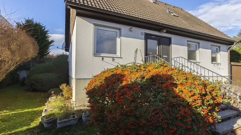 Vorderansicht eines Einfamilienhauses mit gepflegtem Vorgarten und Treppenzugang zum Eingang.