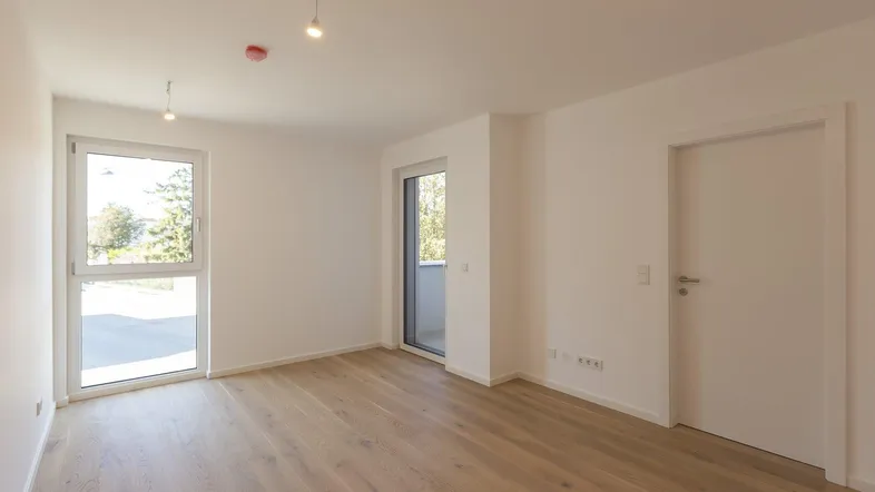 Geräumiges Zimmer mit Holzboden und Zugang zu einem Außenbereich, ideal für flexible Nutzung.