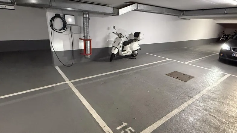 Tiefgaragenstellplatz mit Ladestation für Elektrofahrzeuge und Roller in gut beleuchteter Umgebung.