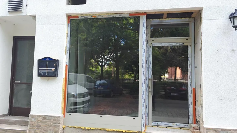 Fassade eines Gebäudes mit neu installierten Fenstern und Tür, die auf eine Straße blicken.
