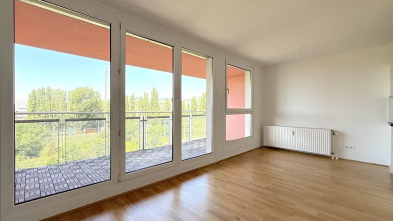 Helles Wohnzimmer mit Parkettboden, großen Fenstern und Zugang zum Balkon.