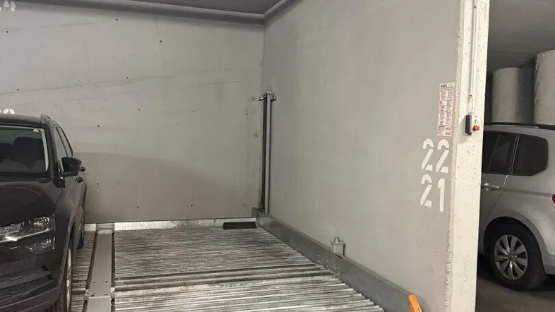 Tiefgarage mit mechanischem Doppelparker-System für zwei Fahrzeuge und Betonboden.
