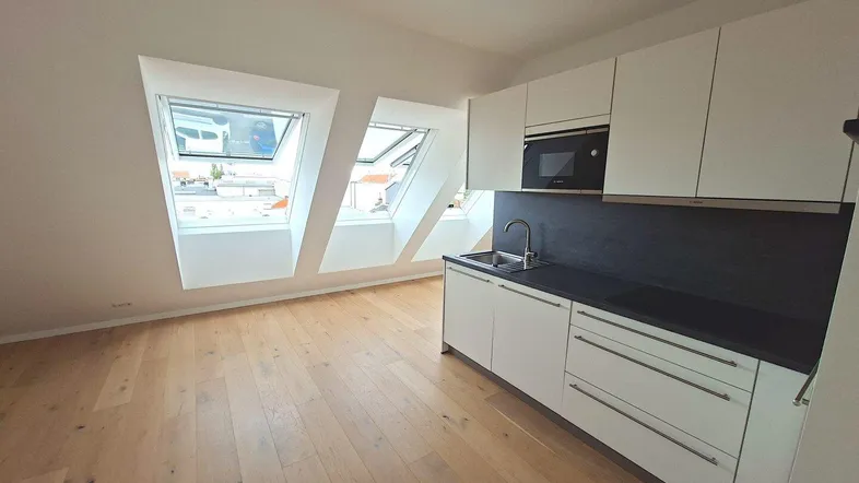 Helle Dachgeschosswohnung mit moderner Küchenzeile, Holzboden und Dachfenstern.