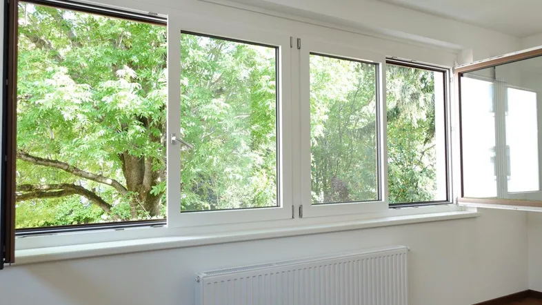Große Fenster mit weißem Rahmen bieten einen schönen Blick ins Grüne.